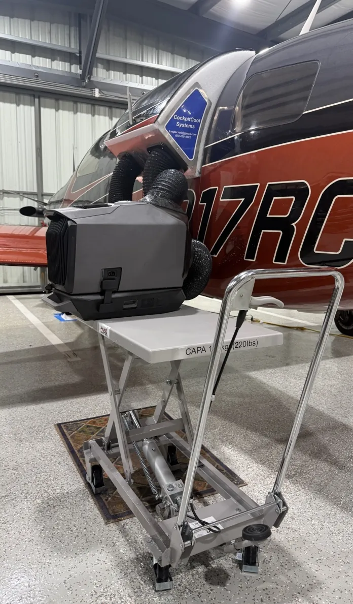 Outside setup: the Wave 3 on a lift cart beside the airplane in a hangar, hoses running up to the plenum in the upper door.